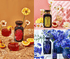 A collage of three images highlights aesthetically arranged bottles from the Gemstone Wellness Bundle: Carnelian, Peridot, Sapphire, featuring vibrant flowers and fruits. The top left showcases a bottle with a red Carnelian label alongside oranges and daisies. The top right displays an organic Peridot tea bundle complemented by white flowers, while the bottom right features a bottle with a blue Sapphire label adorned with blue flowers.