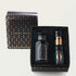 A gift box set labeled "Tea Connoisseur Collection" from Magic Hour contains three items. One is a candle in a black jar with gold accents, another is a small cylindrical container of loose leaf tea with a black lid, and the third item is similar in shape with a part-green, geometric design.